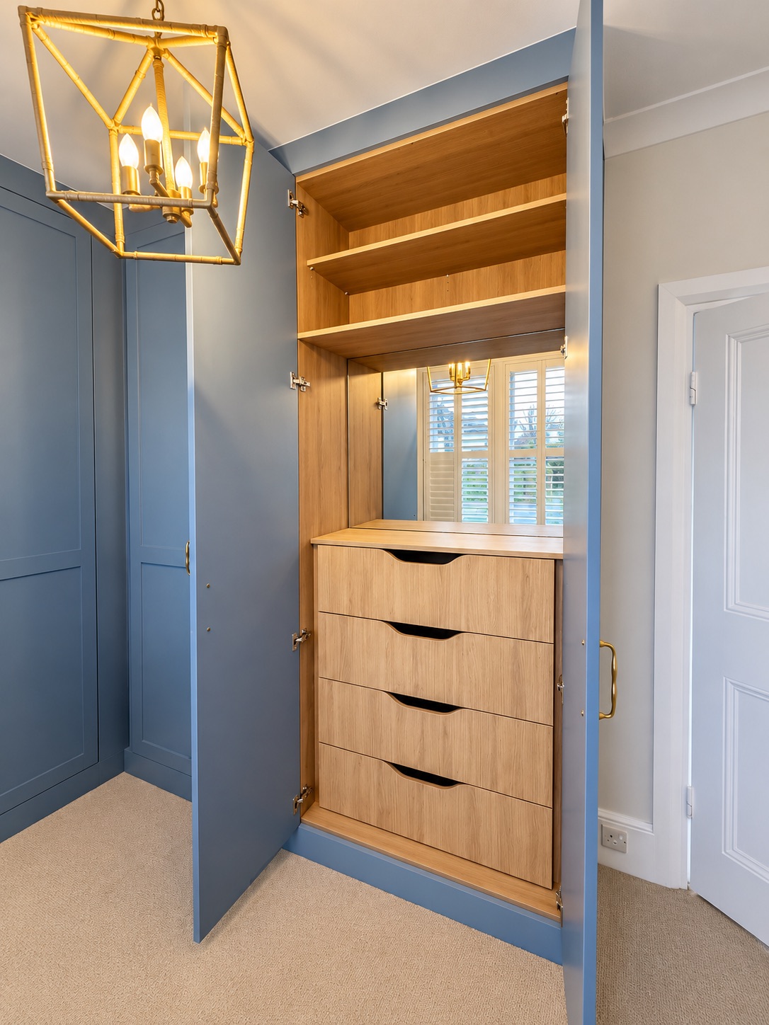 Open Goodwood fitted wardrobe in Southend showing Lancaster Oak drawers, dressing mirror and shelves