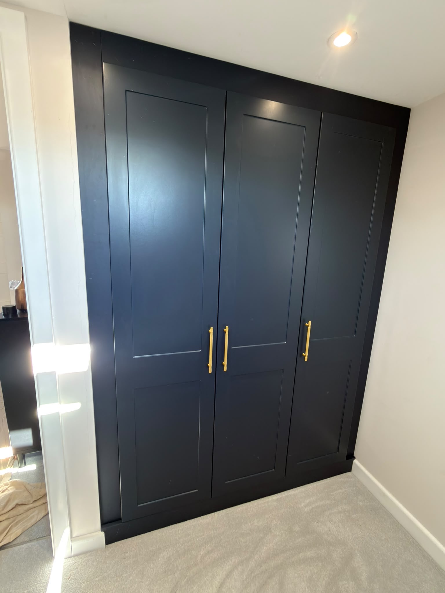 Indigo Blue Rockingham shaker fitted wardrobes with brass handles in a loft bedroom in St Albans