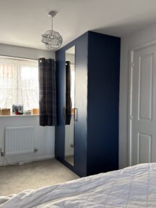 Bespoke Tyrolean Blue wardrobe with full-length mirrored hinged door and antique brass handle in Essex bedroom