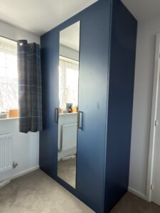 Full-height hinged fitted wardrobe in Tyrolean Blue with mirrored door in a Maldon master bedroom