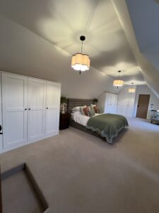 Bedroom featuring a custom-built corner wardrobe with deep hanging space and integrated shelving in textured oak.