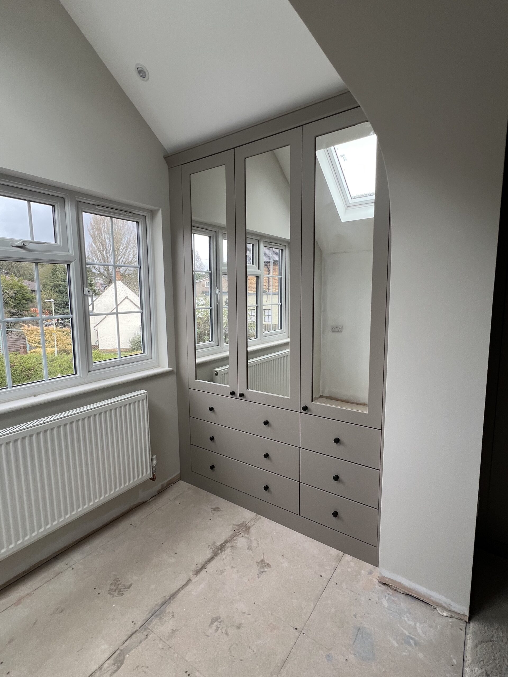Stone Rockingham shaker fitted wardrobes with mirrored upper panels and external drawers beneath a sloping ceiling in Bishop's Stortford